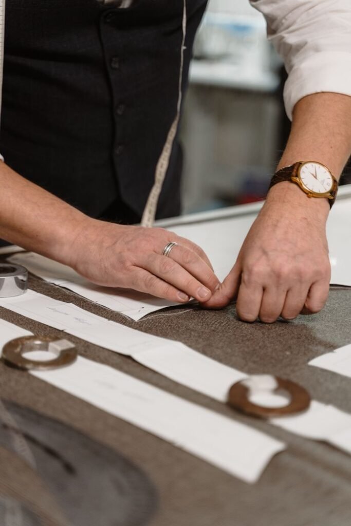 Close-up of a tailor working with fabric and patterns, showcasing skilled craftsmanship.